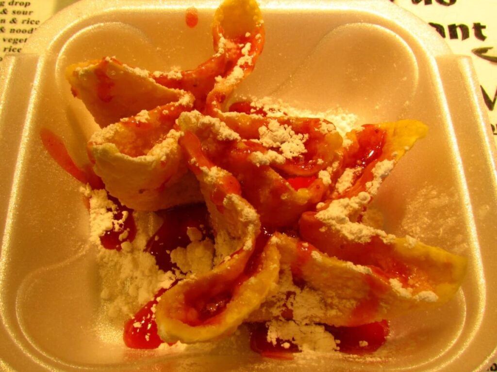 Strawberry cream cheese filled Rangoon are drizzled with a strawberry syrup, and coated with powdered sugar. 