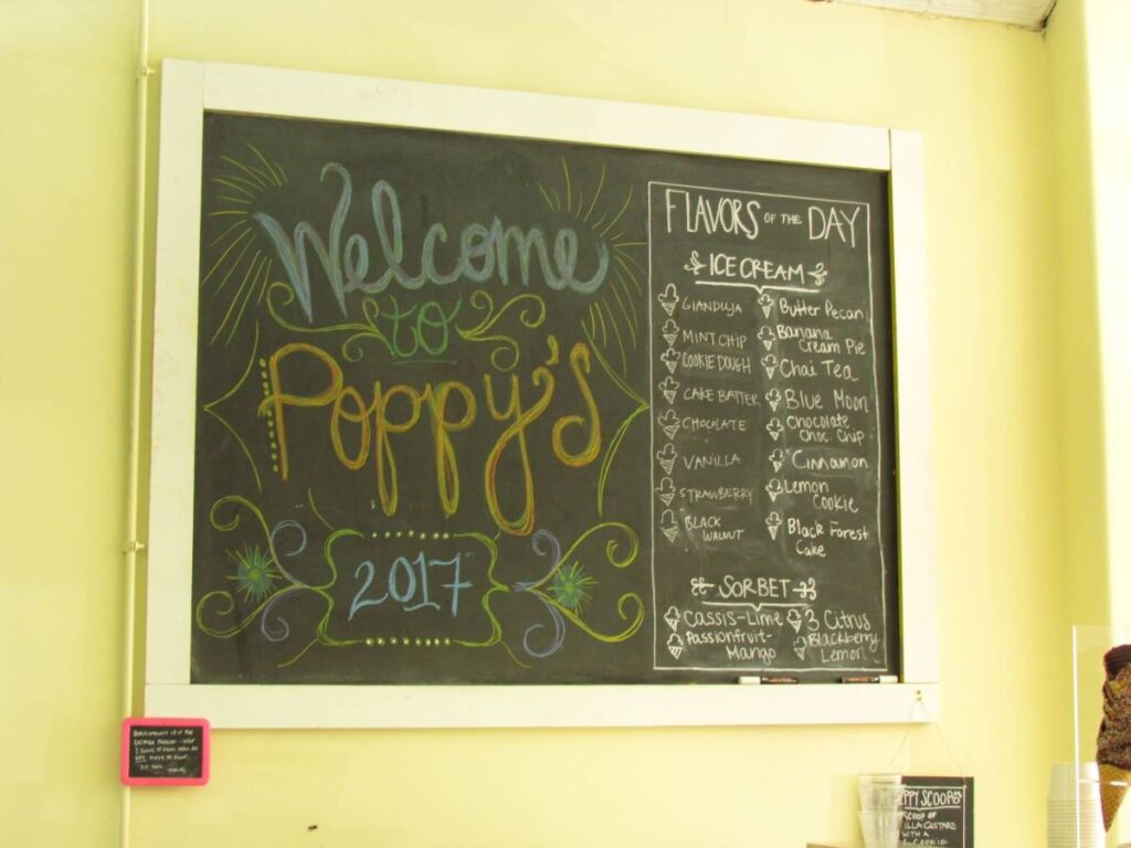An oversized chalkboard is used for a manu board at Poppy's Ice Cream in downtown Lee's Summit. The board contains a list of the currently available flavors of ice cream and sherbert.