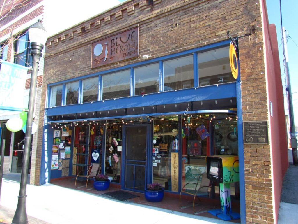 The bright blue trim of the Blue Heron store accents the brick consturction of the building. Large gwindows are filled with colorful items for sale.